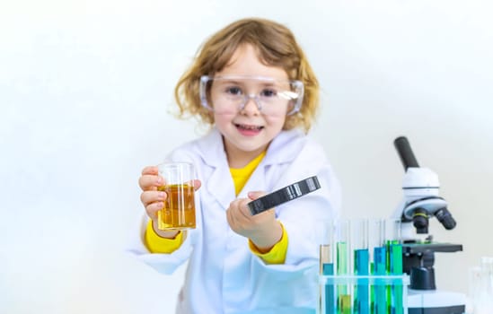 Laboratory examination of a child with test tubes, reagents and a microscope. Selective focus. kid.