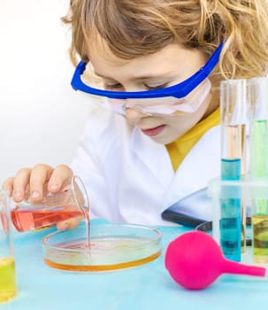 Laboratory examination of a child with test tubes, reagents and a microscope. Selective focus. kid.