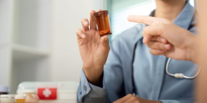 A doctor shows a prescription bottle to a patient, emphasizing communication and understanding in medication management.