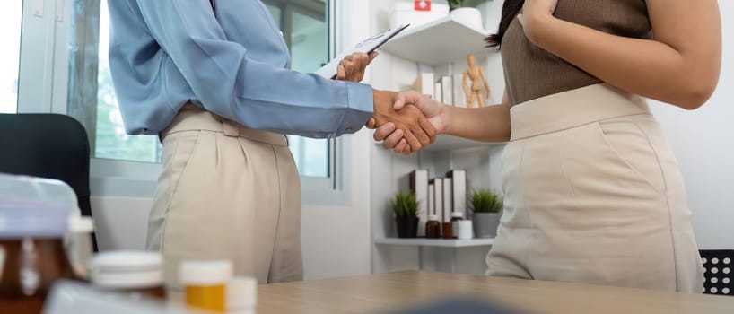A nurse and patient share a handshake, symbolizing trust and collaboration in a healthcare consultation.
