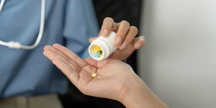 A healthcare provider hands over medication to a patient during a medical consultation, emphasizing patient care and health management.