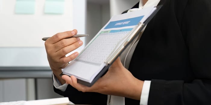 A businesswoman holding a summary report and discussing financial data. Emphasis on accuracy and strategic planning.