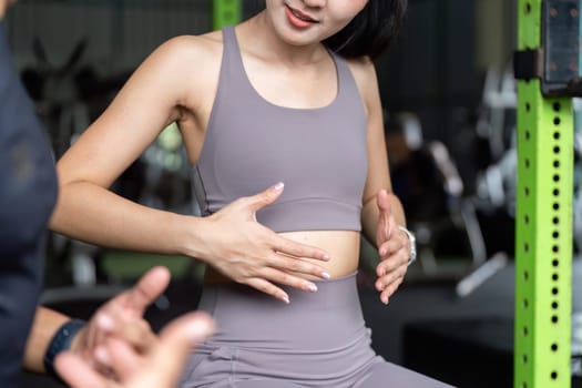 A young woman demonstrates body awareness by focusing on her core strength during a training session with her fitness coach.