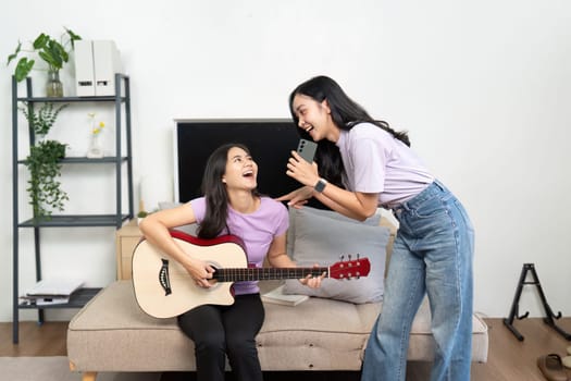 One woman plays guitar while the other sings, creating a joyful atmosphere filled with music and laughter.