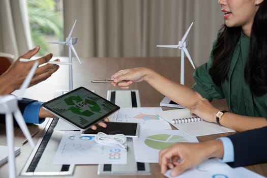 A team of professionals discusses ESG initiatives while analyzing data on a tablet during a strategy meeting.