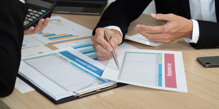 Colleagues analyzing financial documents and summary reports during a business meeting. Focus on collaboration and data-driven decisions.