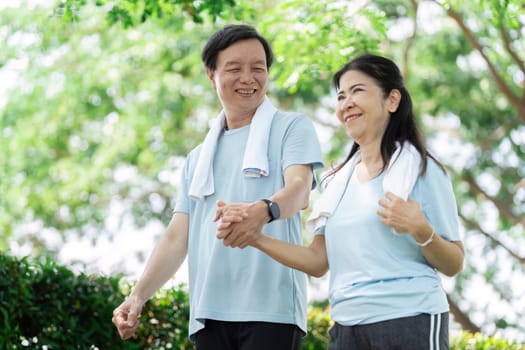 A senior couple strolls hand-in-hand through a park, highlighting the importance of companionship and wellness in their daily lives.