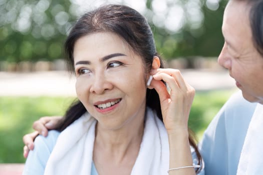 A senior couple shares a moment of connection as they listen to music together while exercising, showcasing the blend of wellness and technology in their active lifestyle.