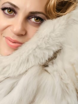 Close up of a beautiful women wearing a fur coat and looking at camera