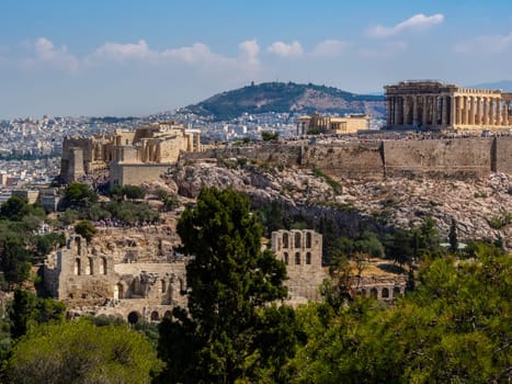 Panoramic view of Athens and Acropolis hill shot from Hill of Muses at clear summer day. Iconic view of ancient ruins and modern city with its main sights.