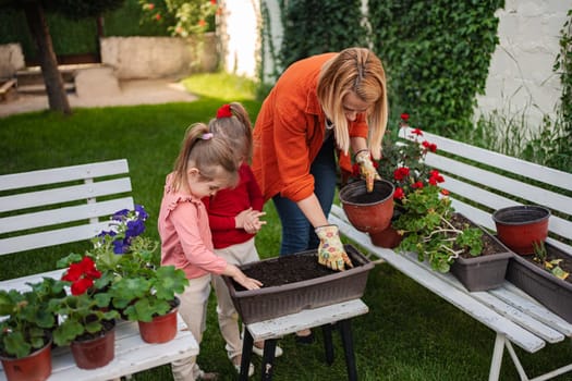 A woman gardens with two young girls in a vibrant backyard.