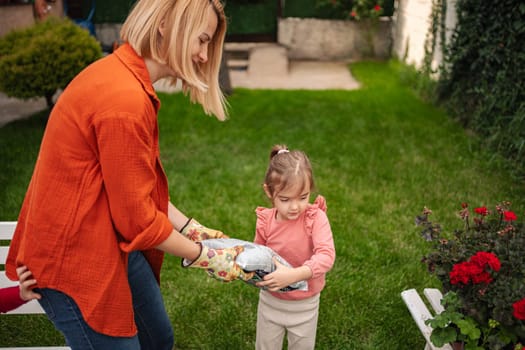 A mother shares a special gardening moment with her daughter.
