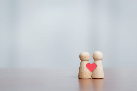 Two wooden figures with heart symbol. Concept of love, connection, relationship, empathy, care, and emotional bonding.