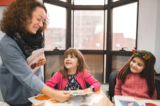 Female teacher helping elementary students at language school class.