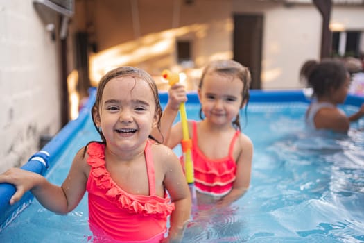 Sisters laugh and play in a vibrant pool during summer fun.