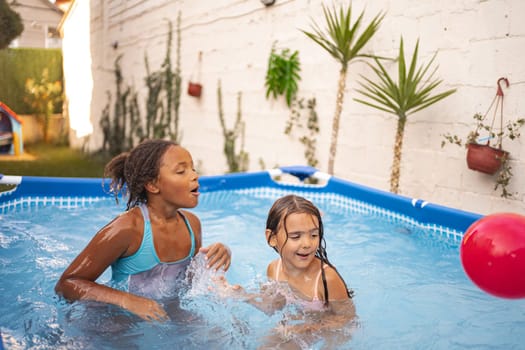 Children have fun playing in a colorful inflatable pool outside.