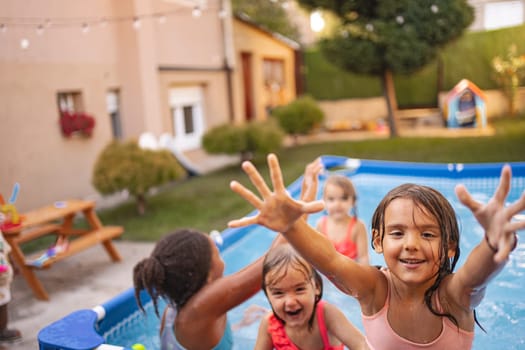 Young kids are splashing and playing happily in the pool outside.
