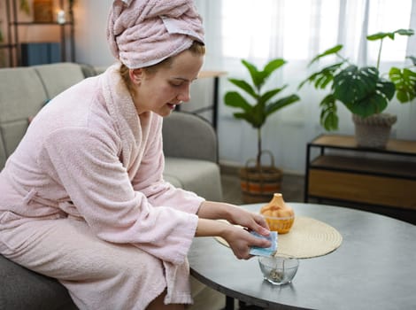 Young woman pouring bath salts into a bowl for aromatherapy at home