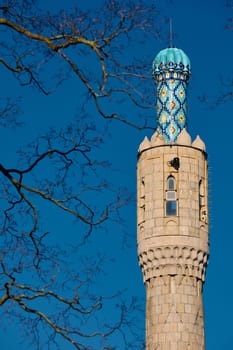 Tower of The blue dome with the golden crescent of the mosque in St.Petersburg - Russia through the branches of trees on a clear spring day. High quality photo