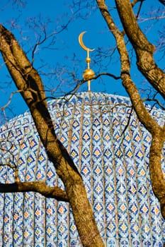 The blue dome with the golden crescent of the mosque in St.Petersburg - Russia through the branches of trees on a clear spring day. High quality photo