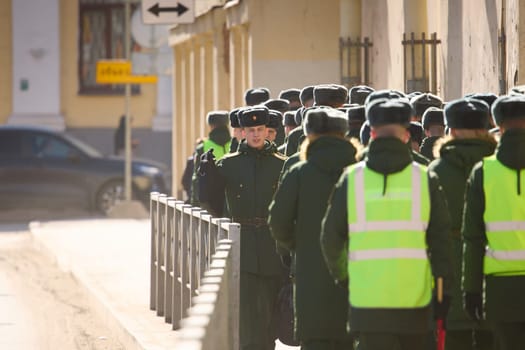 Russia, St.Petersburg, 26 March 2025: a column of cadets of military forces walk along the fence and gates with the symbols of the armed forces. High quality photo