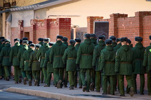 a column of cadets of military forces walk along the fence and gates with the symbols of the armed forces. High quality photo