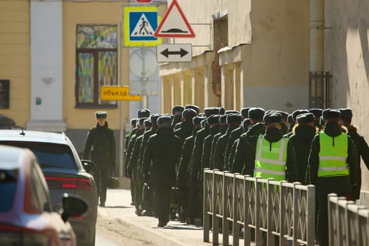 Russia, St.Petersburg, 26 March 2025: a column of cadets of military forces walk along the fence and gates with the symbols of the armed forces. High quality photo