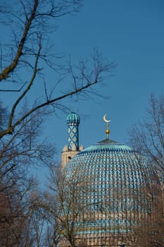 The blue dome with the golden crescent of the mosque in St.Petersburg - Russia through the branches of trees on a clear spring day. High quality photo