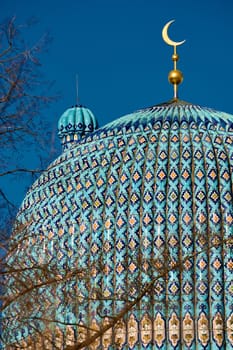 The blue dome with the golden crescent of the mosque in St.Petersburg - Russia through the branches of trees on a clear spring day. High quality photo