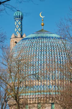 The blue dome with the golden crescent of the mosque in St.Petersburg - Russia through the branches of trees on a clear spring day. High quality photo