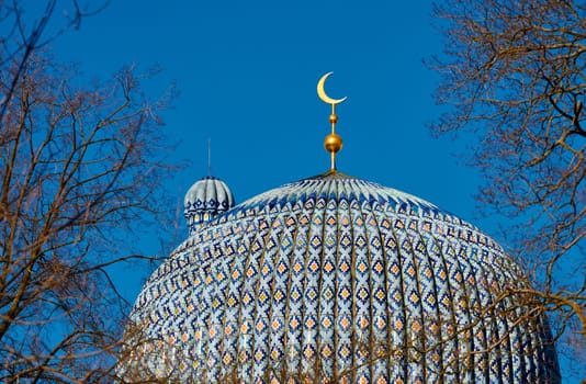 The blue dome with the golden crescent of the mosque in St.Petersburg - Russia through the branches of trees on a clear spring day. High quality photo