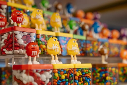 New York City, New York, USA - 07.29.2024: Bright MM's figurines stand on candy containers inside the Times Square store. The vibrant setup showcases red, yellow, and multicolored candies.