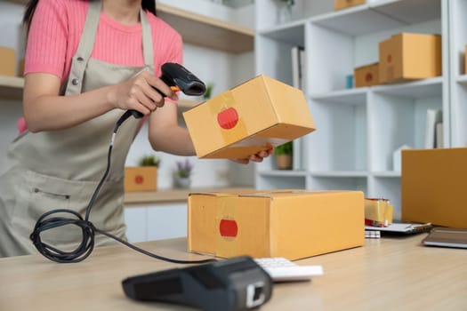 A young woman scans packages with a barcode reader, ensuring efficient inventory tracking in her retail workspace.