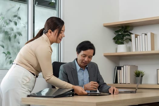 A businesswoman engages with her colleague, presenting important documents and data for financial review in a modern office.
