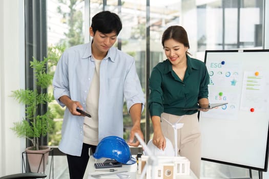 A young team collaborates on an architectural model, focusing on ESG principles and sustainability in a modern workspace.