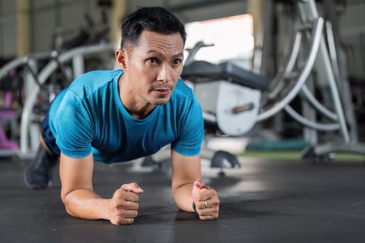 A man performs a plank exercise in a gym, focusing on core strength and stability as part of his fitness routine.