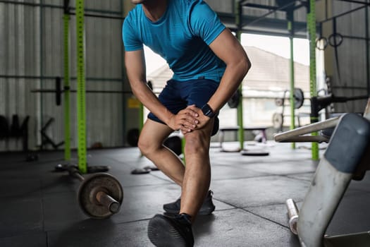 A fit male athlete performs a stretching exercise in a gym, focusing on flexibility and preparation for training.