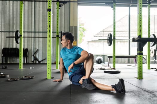 A man engages in a seated stretch in a gym, enhancing flexibility and promoting health. Perfect for fitness visuals.