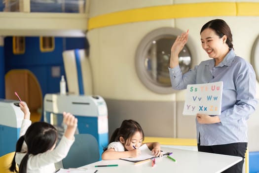 A dedicated teacher enthusiastically instructs young students in an interactive classroom, focusing on learning the alphabet.