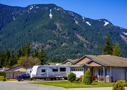 New luxury residential house with car and RV traler parked on driveway. Family house on snow top mountain.