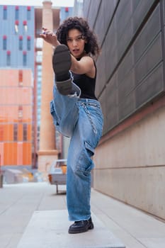 African American woman dancing in a creative pose between benches in an urban setting. he wears casual clothes and shows balance,strength, and expression. Concept of movement, art,and freedom.Vertical