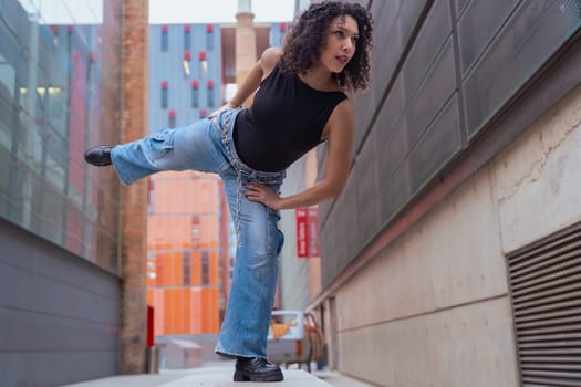 African American woman dancing in a creative pose between benches in an urban setting. he wears casual clothes and shows balance,strength, and expression. Concept of movement, art,and freedom