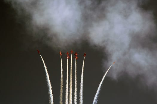Red Arrow Aerobatic Planes Performing a High Altitude Display with Contrail Effects on isolated color, Aerobatic planes showcase a stunning high altitude routine, leaving white contrails against the sky, demonstrating precise coordination and aerial artistry in a captivating airborne spectacle.