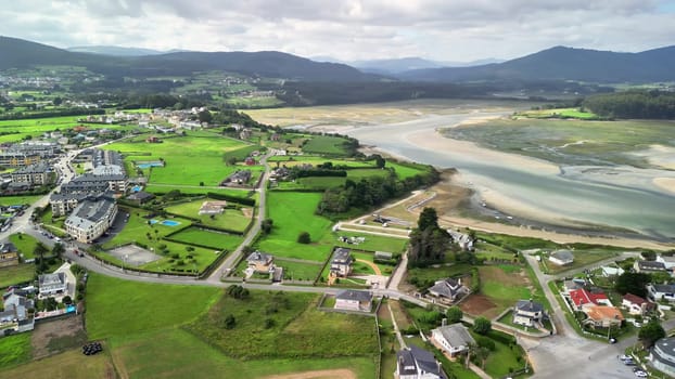 This stunning aerial viewpoint reveals a picturesque coastal village, an estuary, and lush, green landscapes