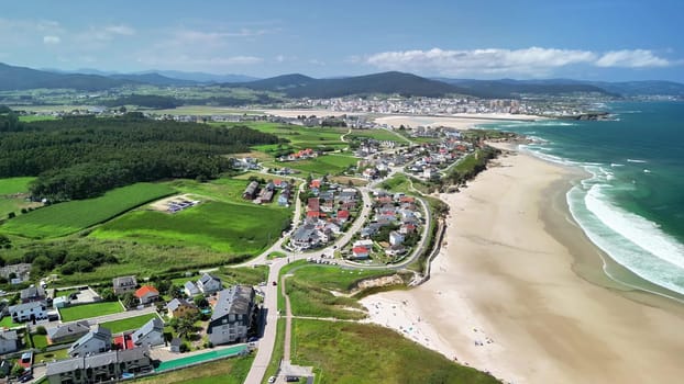 The vibrant aerial view shows a picturesque coastal town with inviting sandy beaches and lush greenery
