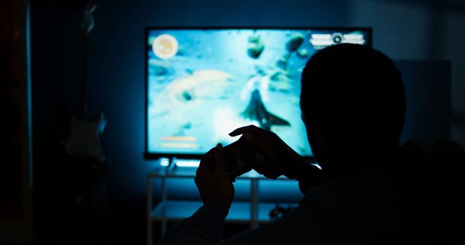 Guy spends time on television playing multiplayer web video games, setting his console into smart tv and having fun gaming at night. Player battling in shooter competition. Camera A.