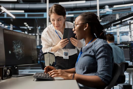 Data center technicians look at visualization on PC screen to pinpoint equipment performance issues. Server hub teamworking colleague look at data analysis graph to reduce hardware failures