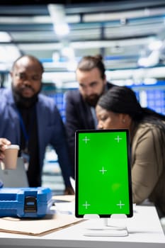 Solar panel inspection group review data on pc next to green screen, finding errors during a process audit and helping optimize renewable energy operations. Photovoltaics factory.
