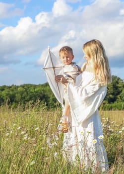 A small child in his mother's arms, they are having fun in the meadow, flying a kite. High quality photo