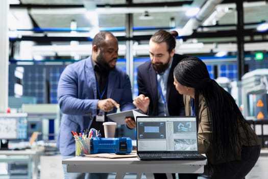 Multiethnic specialists engineers doing teamwork on modern production line for solar panels power, combining technical insight and collaboration for renewable energy infrastructure.